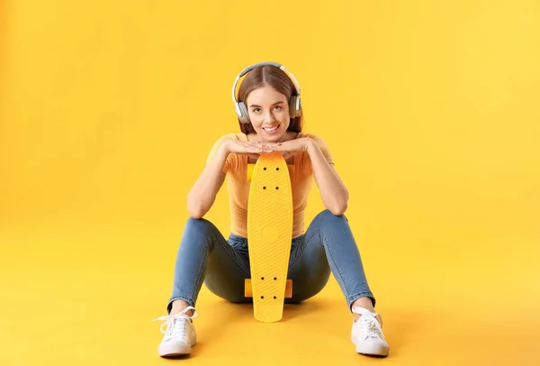 Stylish hipster girl with skateboard on color background — Stock Photo, Image