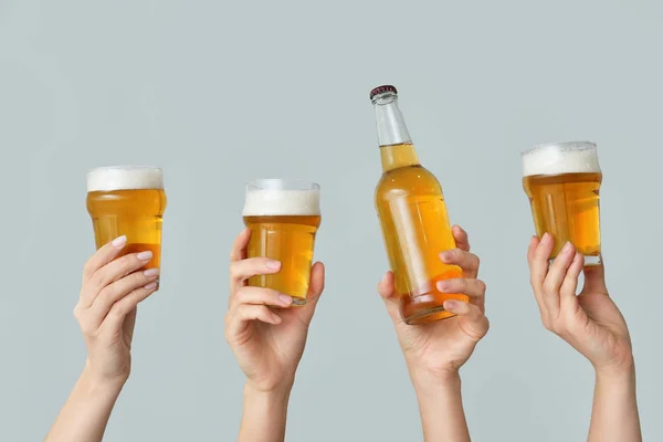 Ręce ze świeżym piwem na szarym tle — Zdjęcie stockowe
