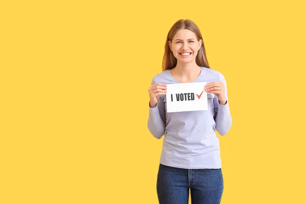 Jovem segurando papel com texto I VOTED em fundo de cor — Fotografia de Stock