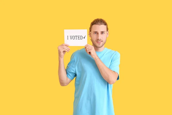 Joven sosteniendo papel con texto Voté sobre fondo de color — Foto de Stock