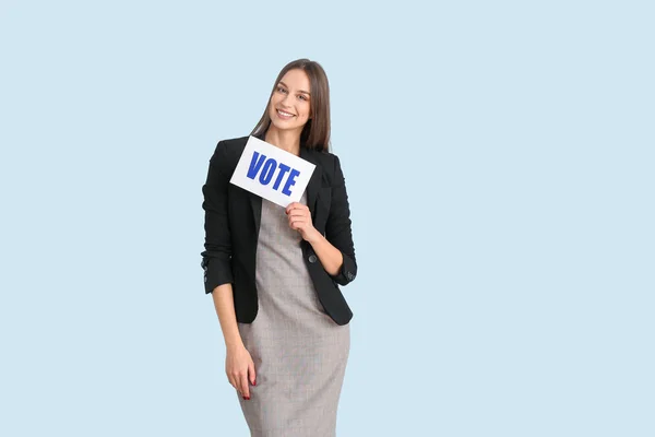 Giovane donna in possesso di carta con testo VOTO su sfondo a colori — Foto Stock