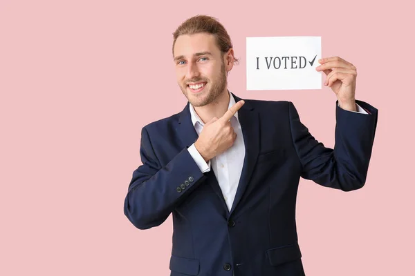 Young businessman holding paper with text I VOTED on color background — Stock Photo, Image