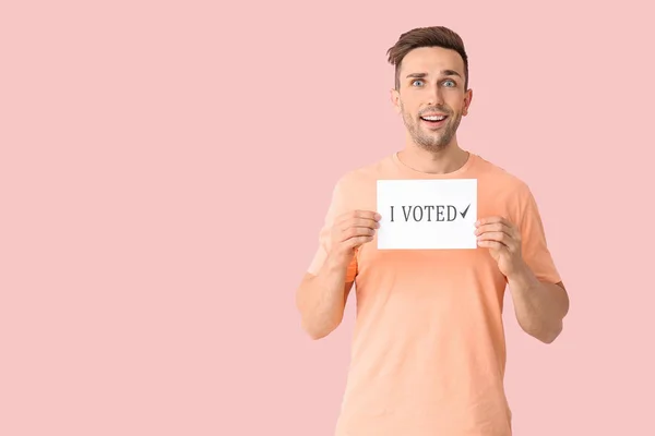 Young man holding paper with text I VOTED on color background — Stock Photo, Image