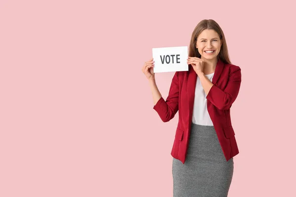 Mujer joven sosteniendo papel con texto VOTO sobre fondo de color —  Fotos de Stock