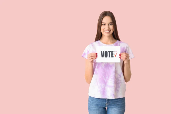Young woman holding paper with text VOTE on color background — Stock Photo, Image