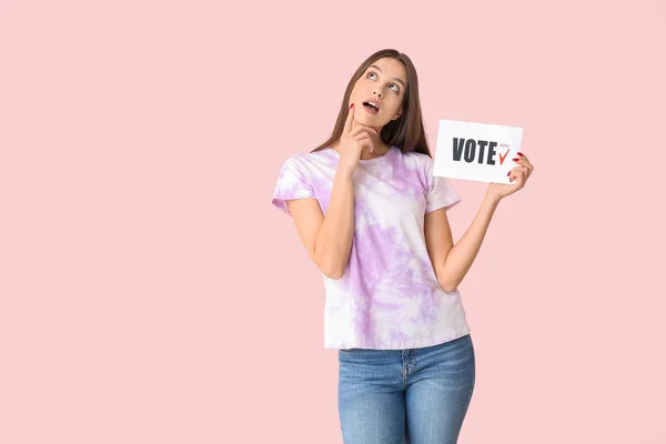 Mulher atenciosa segurando papel com texto VOTE no fundo de cor — Fotografia de Stock