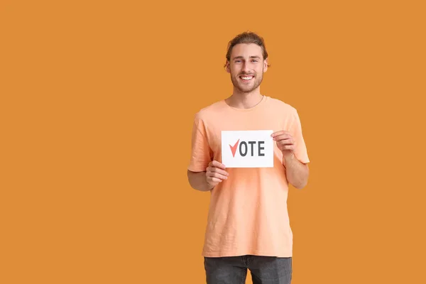 Young man holding paper with text VOTE on color background — Stock Photo, Image