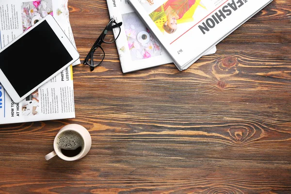 Periódicos, tableta y taza de café sobre fondo de madera — Foto de Stock