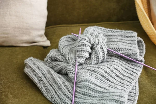 Polohotový pletený svetr s jehlicemi doma na gauči — Stock fotografie