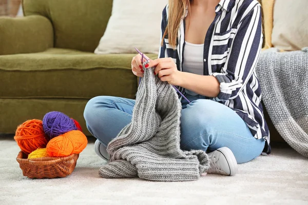 Young woman knitting warm sweater at home