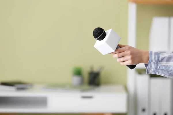 Female journalist with microphone having an interview indoors — Stock Photo, Image