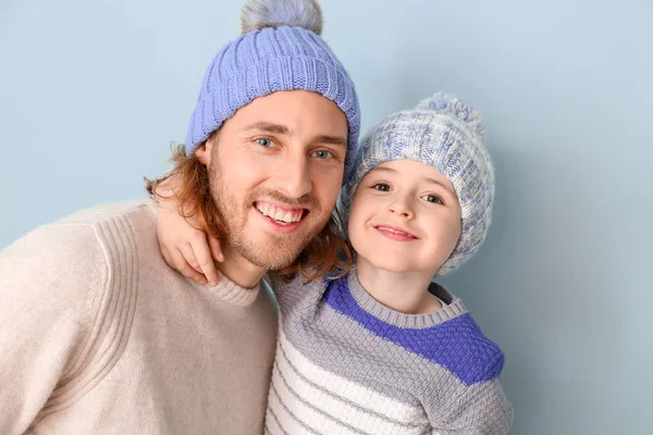 Man och hans lilla son i vinterkläder på färg bakgrund — Stockfoto