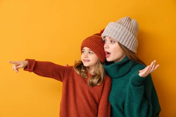 Mulher e sua filhinha em roupas de inverno no fundo de cor — Fotografia de Stock