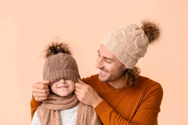 Homem e seu filho em roupas de inverno em fundo de cor — Fotografia de Stock