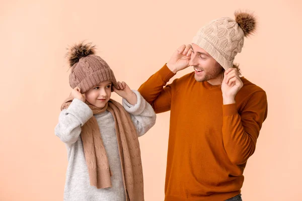 Homem e seu filho em roupas de inverno em fundo de cor — Fotografia de Stock
