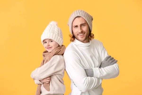 Mann und sein kleiner Sohn in Winterkleidung auf farbigem Hintergrund — Stockfoto