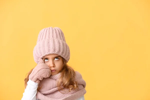 Omtenksom liten jente i vinterklær på farget bakgrunn – stockfoto