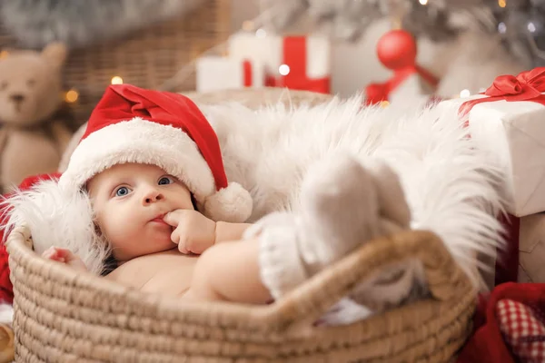 Bebê bonito com chapéu de Papai Noel deitado em cesta em casa — Fotografia de Stock