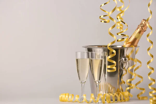 Eimer mit Flasche Champagner, Gläsern und Weihnachtsdekor auf hellem Hintergrund — Stockfoto