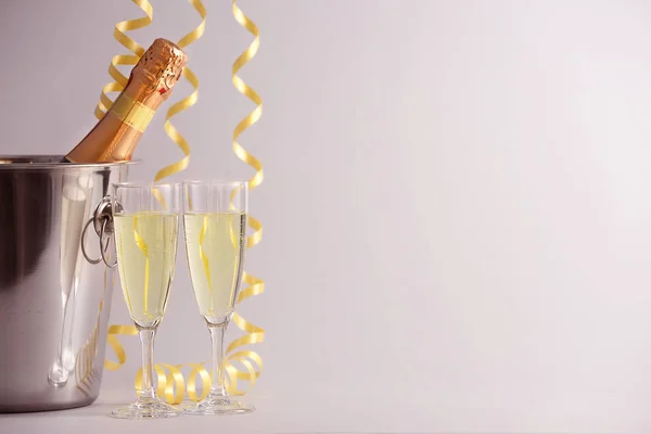 Eimer mit Flasche Champagner, Gläsern und Weihnachtsdekor auf hellem Hintergrund — Stockfoto