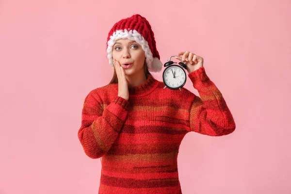 Překvapená mladá žena v klobouku Santa a s budíkem na barevném pozadí. Koncept vánočního odpočítávání — Stock fotografie