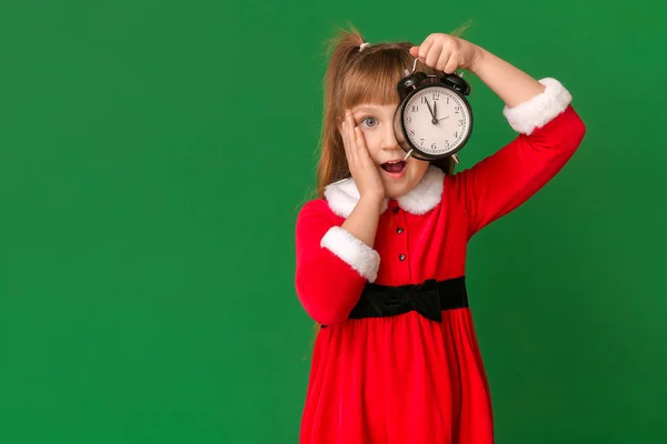 Överraskad liten flicka i Santa kostym och med väckarklocka på färg bakgrund. Julnedräkning koncept — Stockfoto