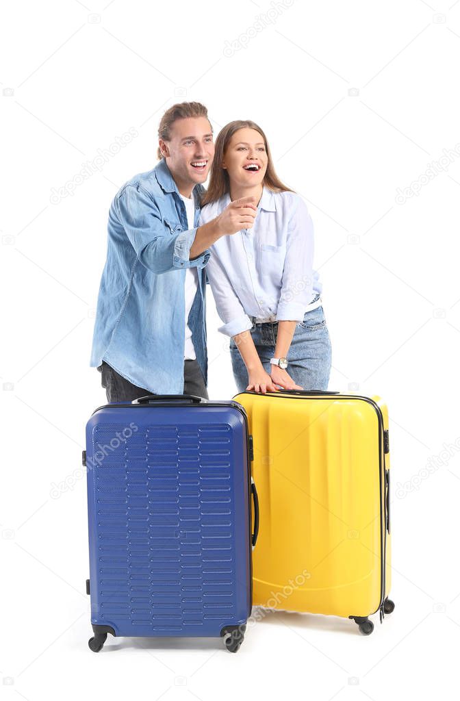 Young couple with suitcases on white background