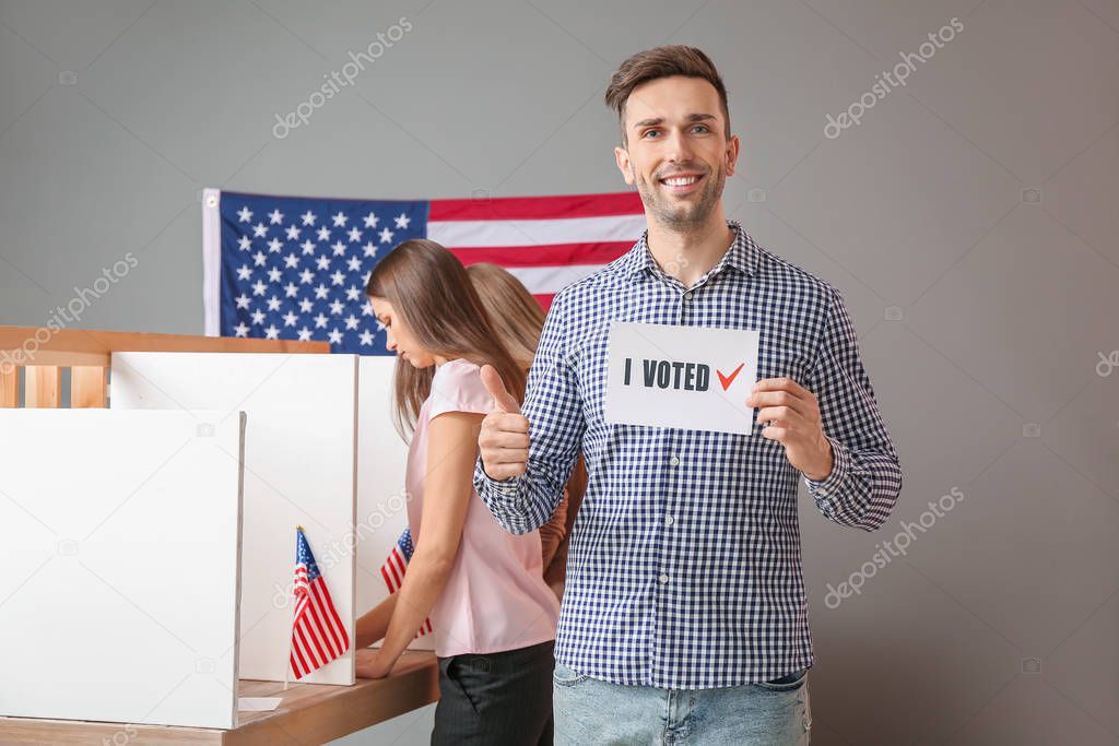 Young man holding paper with text I VOTED at USA polling station