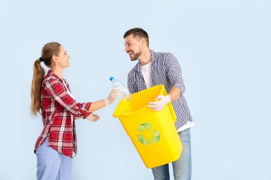 Renkli arka planda çöp konteynırı olan bir çift. Geri dönüşüm kavramı