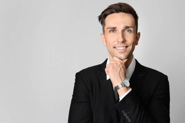 Gri arka planda yakışıklı genç iş adamı