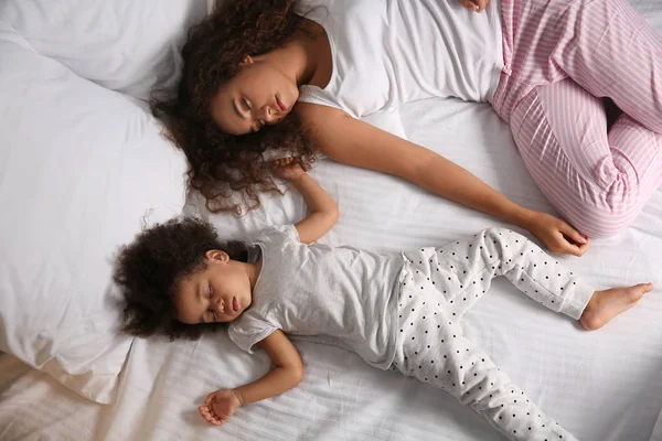 Niña afroamericana con madre durmiendo en la cama por la noche — Foto de Stock