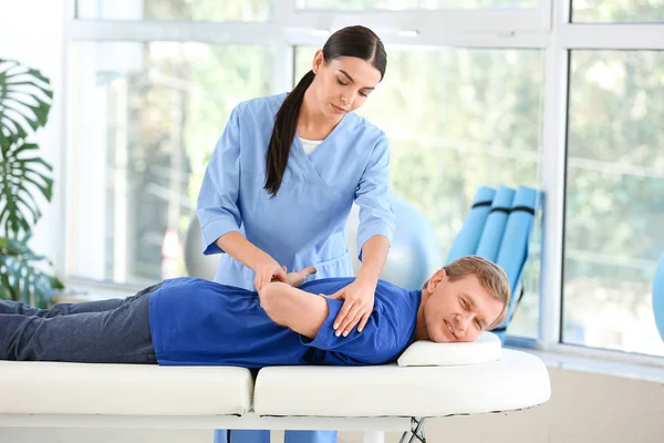 Fysiotherapeut werkt met mannelijke patiënt in revalidatiecentrum — Stockfoto
