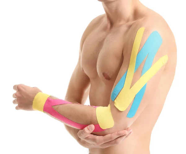 Sporty man with physio tape applied on arm against white background, closeup — Stock Photo, Image