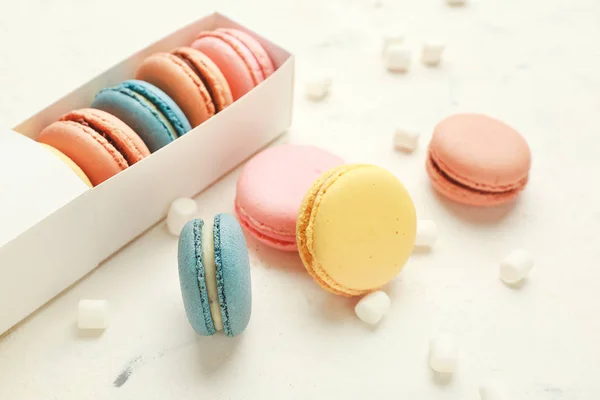 Doos met verschillende smakelijke macarons en marshmallows op witte achtergrond — Stockfoto