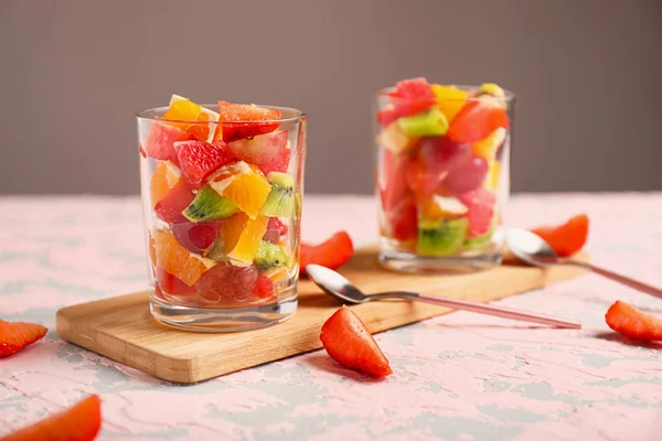 Gafas con sabrosa ensalada de frutas en la mesa —  Fotos de Stock