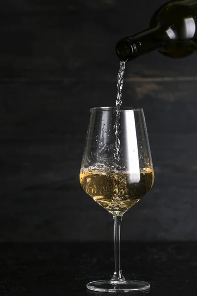 Pouring of tasty wine into glass against dark background — Stock Photo, Image