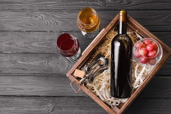 Box with bottle and glasses of different wine on wooden table — Stockfoto