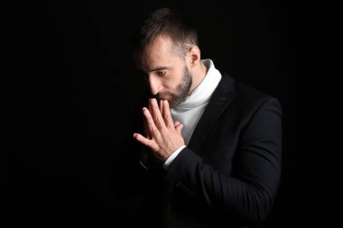 Karanlık arka planda dua eden genç adamın portresi