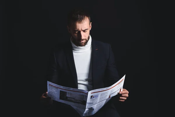 Retrato de un joven con estilo leyendo el periódico sobre fondo oscuro — Foto de Stock