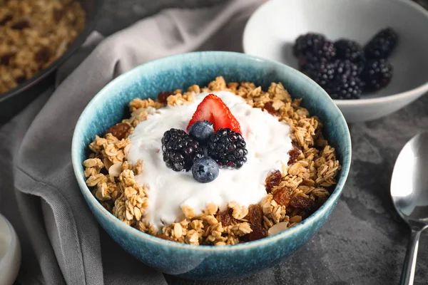 Tasty granola with yogurt in bowl on grey background — Stock Photo, Image
