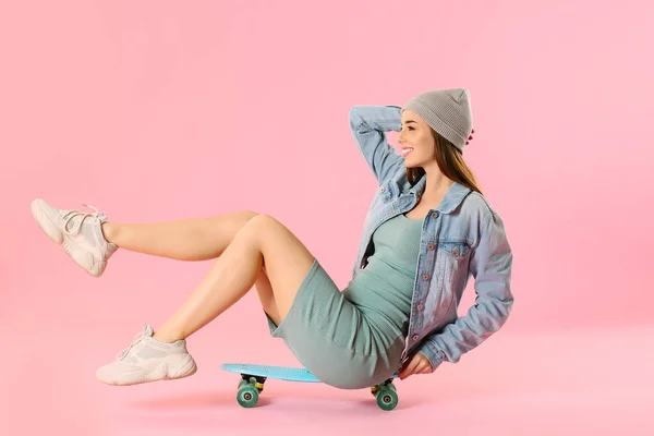 Stylish hipster girl with skateboard on color background — Stock Photo, Image