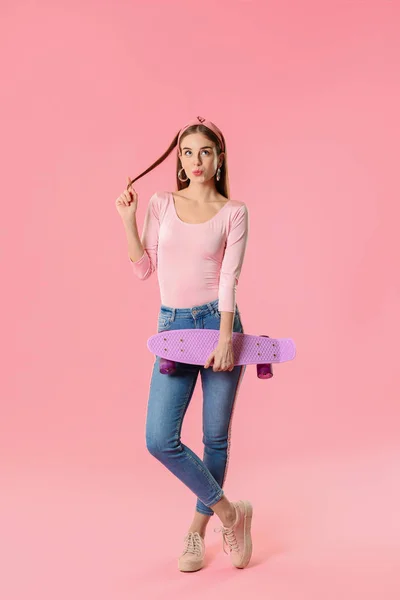 Chica hipster reflexivo con monopatín sobre fondo de color —  Fotos de Stock