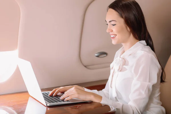 Businesswoman with laptop on board the modern private airplane
