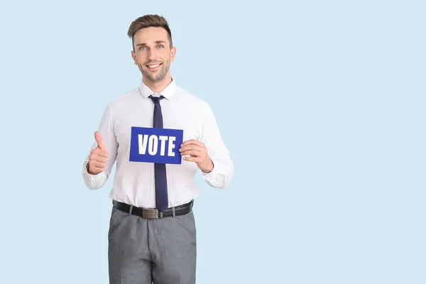 Empresário segurando papel com texto VOTE e mostrando thumb-up no fundo de cor — Fotografia de Stock
