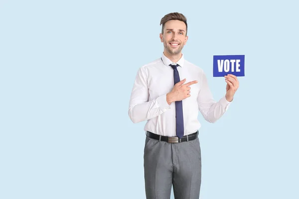 Empresário segurando papel com texto VOTE sobre fundo de cor — Fotografia de Stock