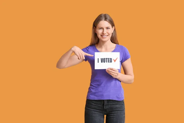 Jovem segurando papel com texto I VOTED em fundo de cor — Fotografia de Stock