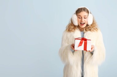 Kış kıyafetleri içinde mutlu genç bir kadın ve renkli bir Noel hediyesi.