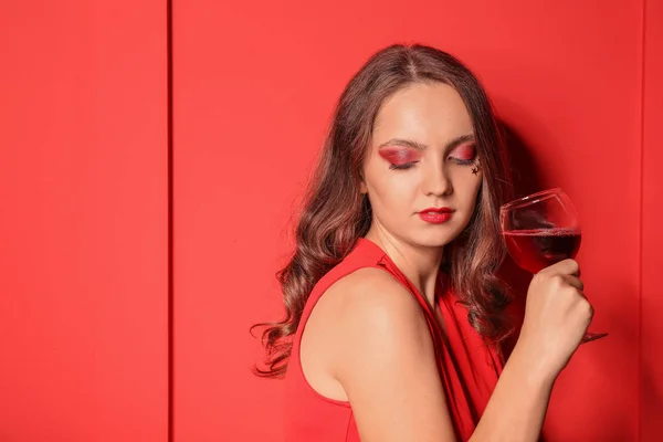 Fashionable young woman with glass of wine near color wall — Stock Photo, Image