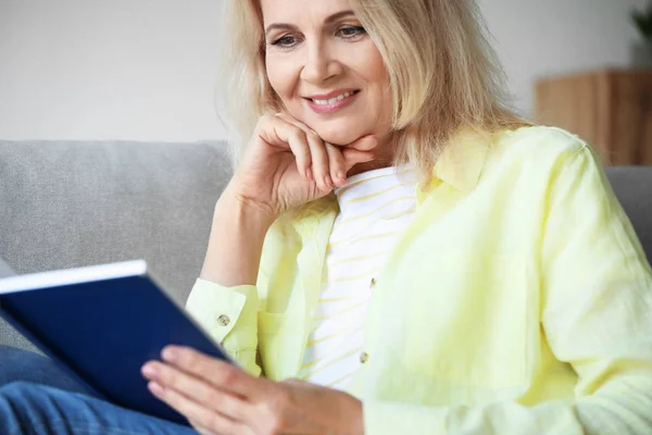 Gyönyörű érett nő olvas könyvet otthon — Stock Fotó