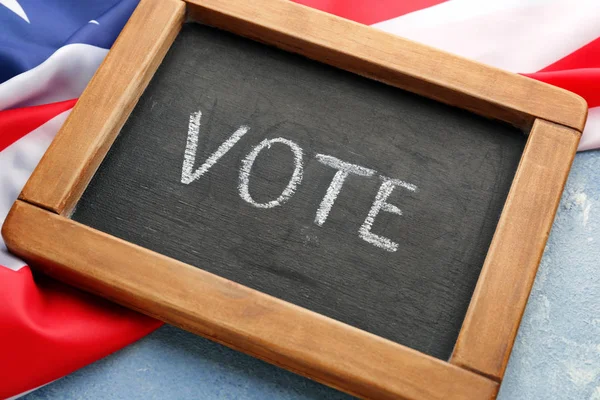 Chalkboard with text VOTE and USA flag on color background — Stockfoto